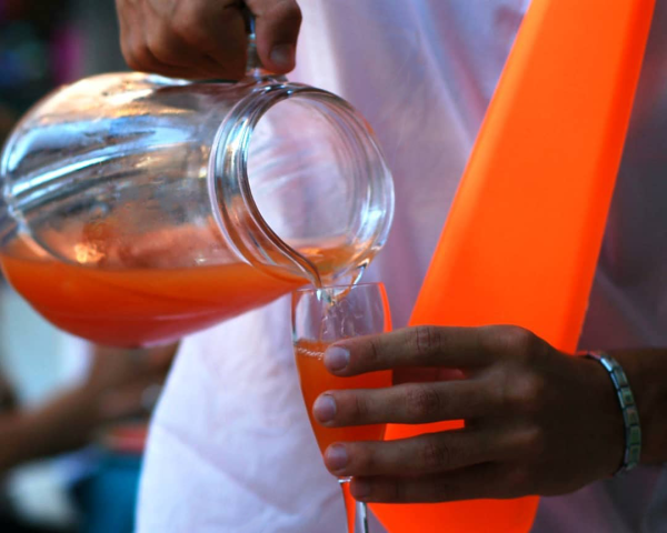 Versando una bevanda arancione in un bicchiere con un cono arancione.