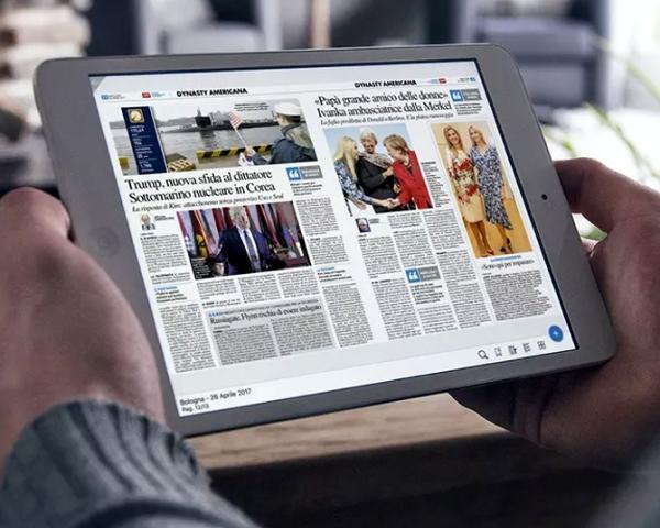 Persona legge un giornale su tablet in una stanza luminosa.